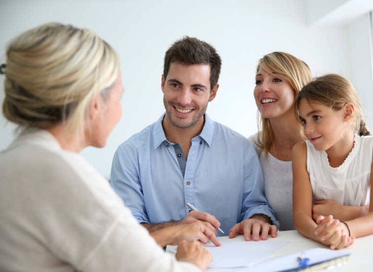 A family sits at a table and talks to a real estate agent about their credit score.