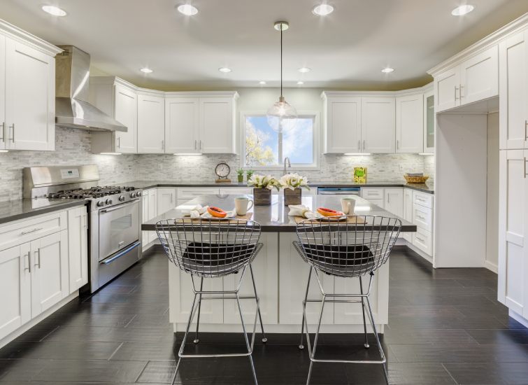 A rental kitchen with white cabinets and black counter tops.