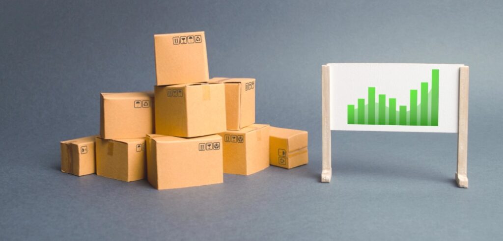 A stack of cardboard boxes is placed next to a small easel holding a whiteboard with a green bar chart on it.